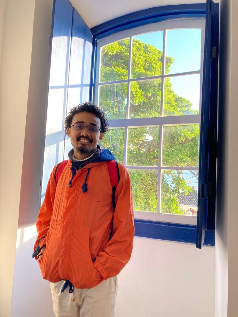 Técnico de TI sorrindo próximo à janela representando atendimento humano e acessível